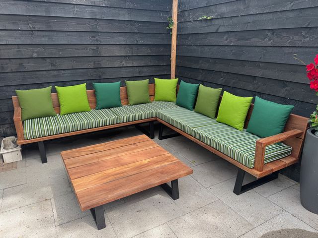 Houten hoek loungeset op maat met groene kussens en bijpassende salontafel