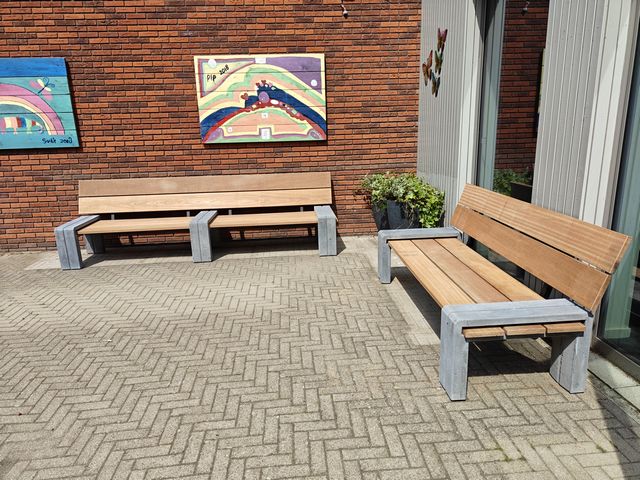 Houten buitenbanken met robuuste betonnen poten geplaatst op een schoolplein