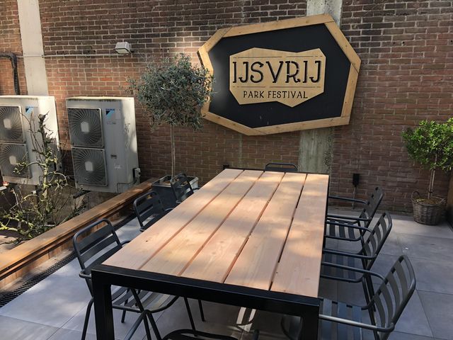 Grote houten buitentafel op maat met zwart stalen frame voor een horecaterras