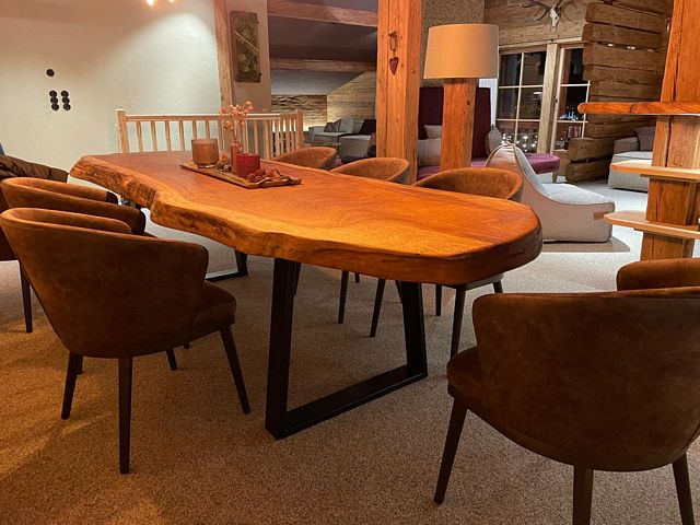 Massieve houten boomstam eettafel met natuurlijke randen en zwart stalen onderstel in een interieur