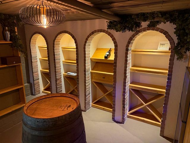 Maatwerk houten wijnkast met wijnrekken en opbergruimte in een sfeervolle wijnkamer