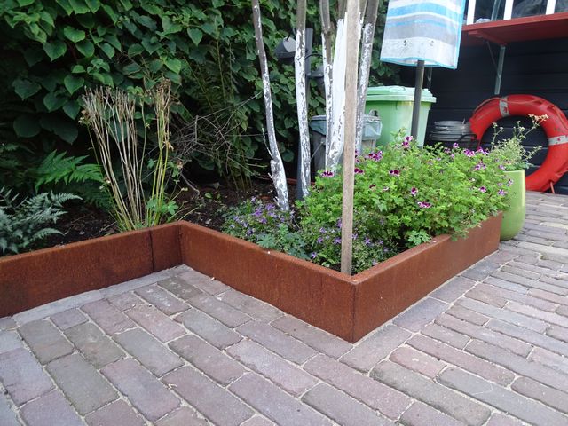 Cortenstalen borderrand op maat rond beplanting als afscheiding tussen tuin en bestrating