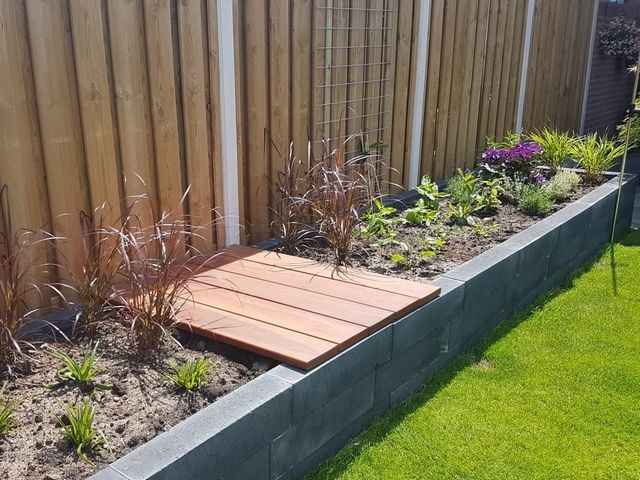 Maatwerk houten vlonder in een verhoogde border met beplanting in de tuin
