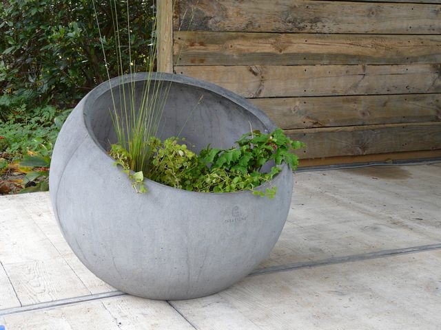 Grote ronde betonnen plantenbak met groene beplanting als decoratieve plantenbak op het terras