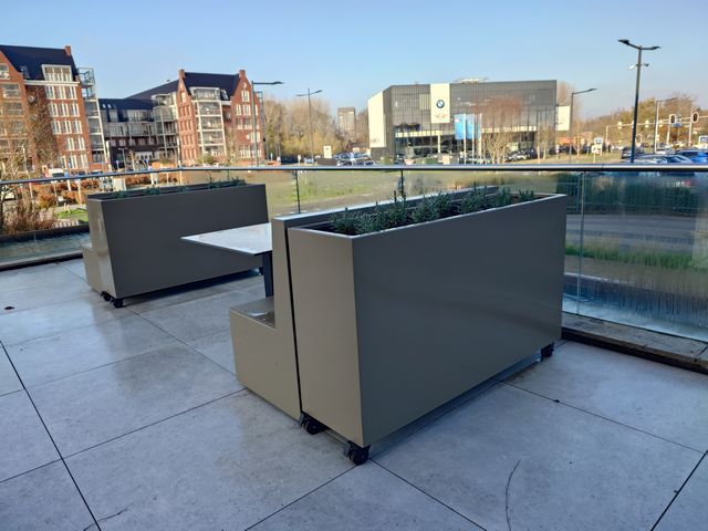 Grote stalen plantenbakken met wielen op een hotelterras