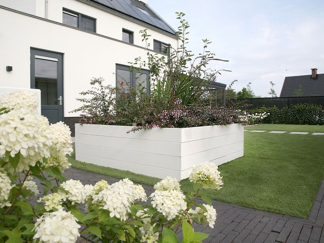 Grote witte stalen plantenbak met beplanting in een moderne tuin