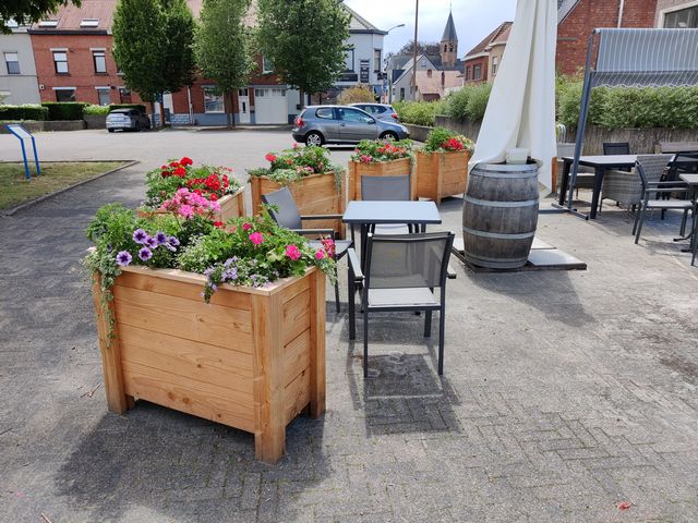 Houten plantenbakken met kleurrijke bloemen als groene afscheiding op een horecaterras
