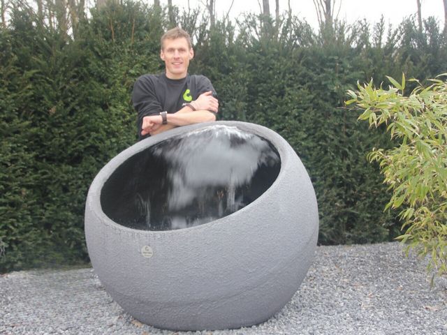 Groot rond waterornament met waterval als blikvanger in een moderne tuin